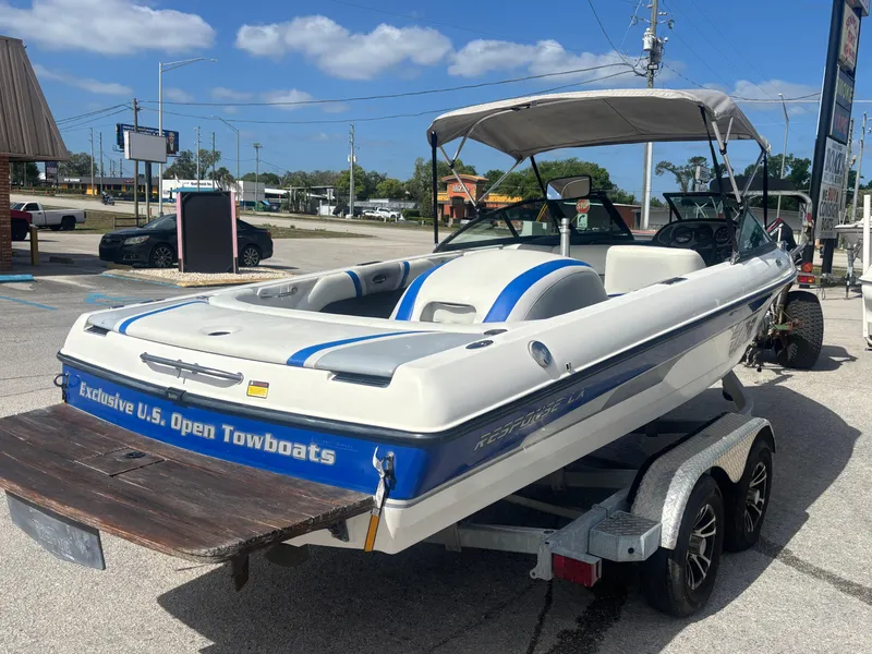 Slide: The Image of 2001 Malibu Response LX boat on trailer, white with blue accents, parked outdoors. - 14