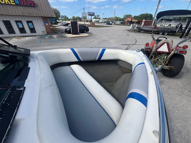 Slide: The Image of 2001 Malibu Response LX boat interior with blue and white seating, parked near a store. - 21
