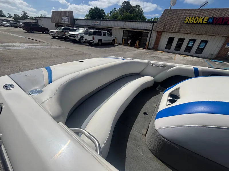 Slide: The Image of 2001 Malibu Response LX boat interior with white and blue seating, parked near shops. - 23