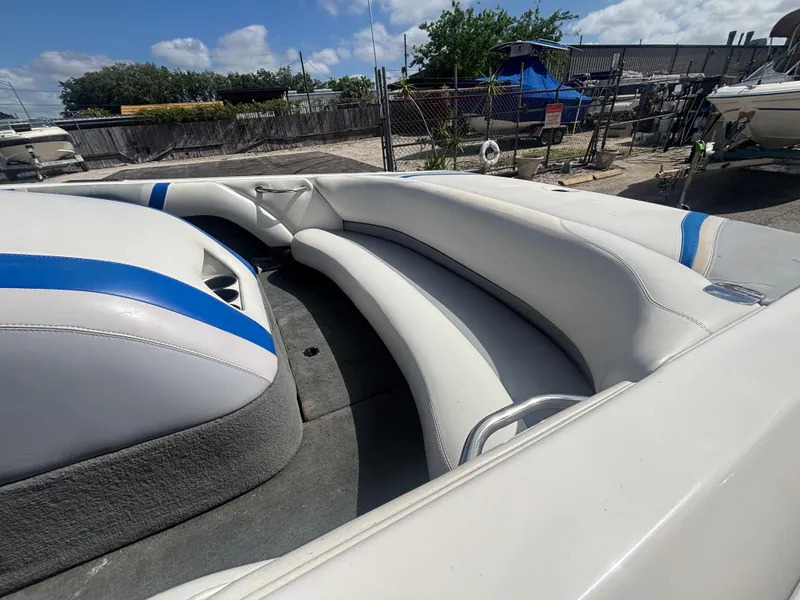 Slide: The Image of 2001 Malibu Response LX boat interior with white and blue seating, parked outdoors. - 25