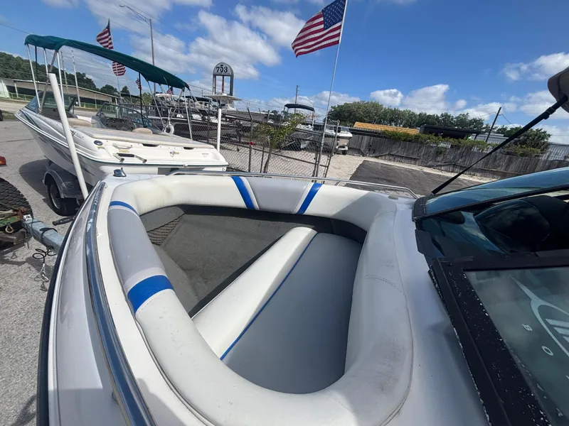 Slide: The Image of 2001 Malibu Response LX boat with white and blue interior, parked near American flags. - 28