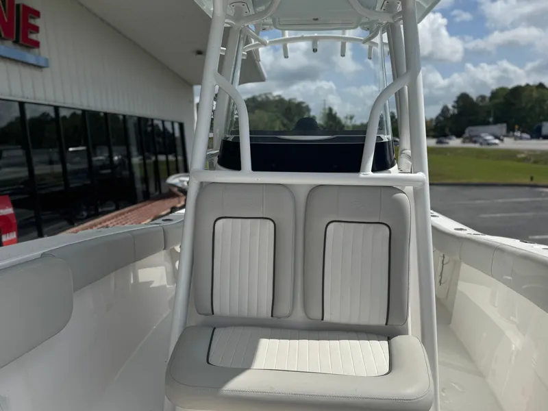 Slide: The Image of 2021 Sea Fox 228 Commander boat interior with cushioned seating and T-top under a cloudy sky. - 8