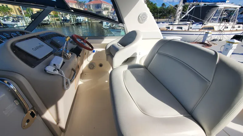 Slide: The Image of 2001 Sea Ray 310 Sundancer cockpit with steering wheel and seating, docked at marina. - 11