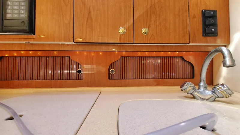 Slide: The Image of Interior of 2001 Sea Ray 310 Sundancer showing wooden cabinets and kitchen sink. - 23