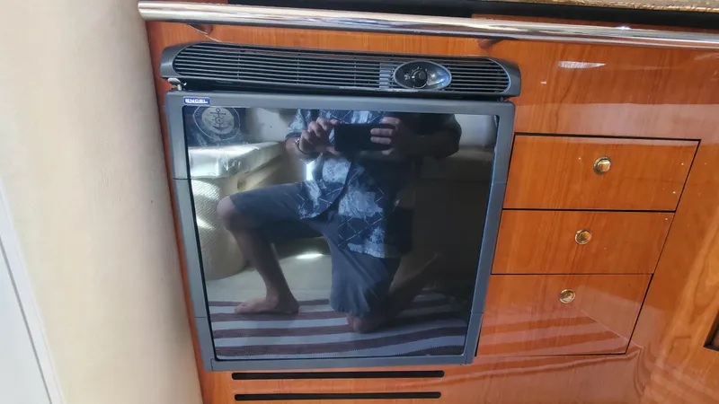 Slide: The Image of 2001 Sea Ray 310 Sundancer interior with a compact refrigerator and wooden cabinetry. - 30