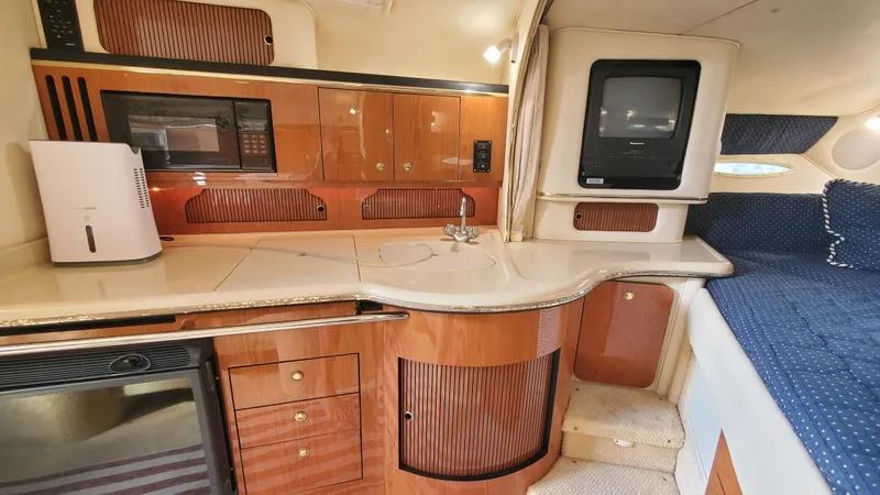 Slide: The Image of 2001 Sea Ray 310 Sundancer interior with kitchenette, wood cabinetry, and cozy seating area. - 40