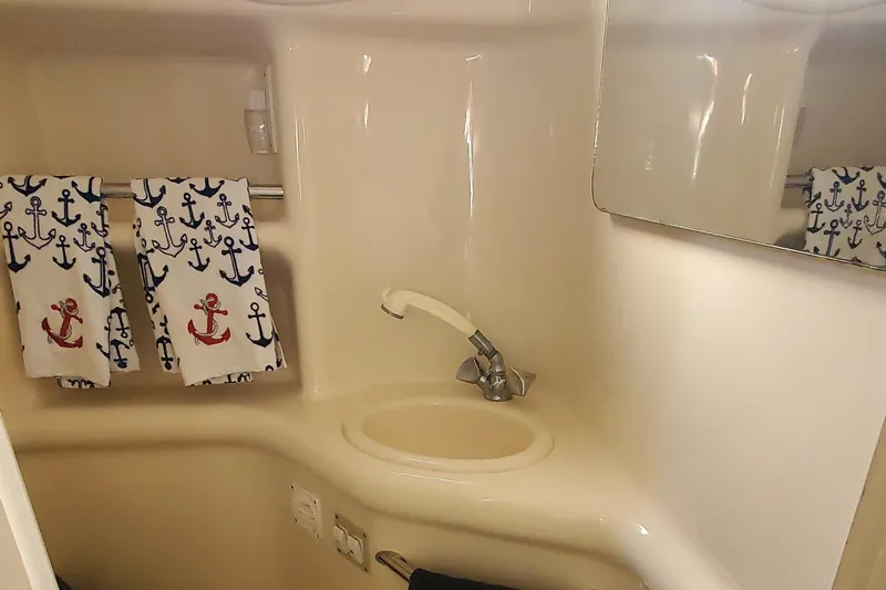 Slide: The Image of 2001 Sea Ray 310 Sundancer bathroom with anchor-themed towels and compact sink. - 49