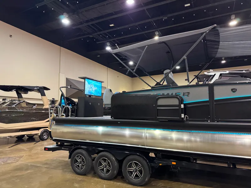 Slide: The Image of 2025 Premier 250 Solaris Rear Social pontoon boat displayed indoors on a trailer. - 10
