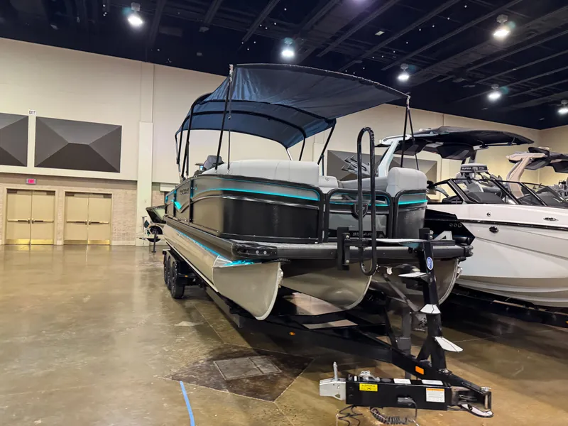Slide: The Image of 2025 Premier 250 Solaris Rear Social pontoon boat displayed indoors with canopy. - 3