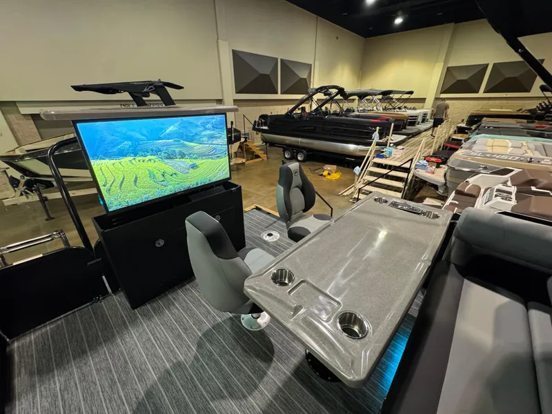 Slide: The Image of 2025 Premier 250 Solaris Rear Social boat interior with seating, table, and large screen display. - 40