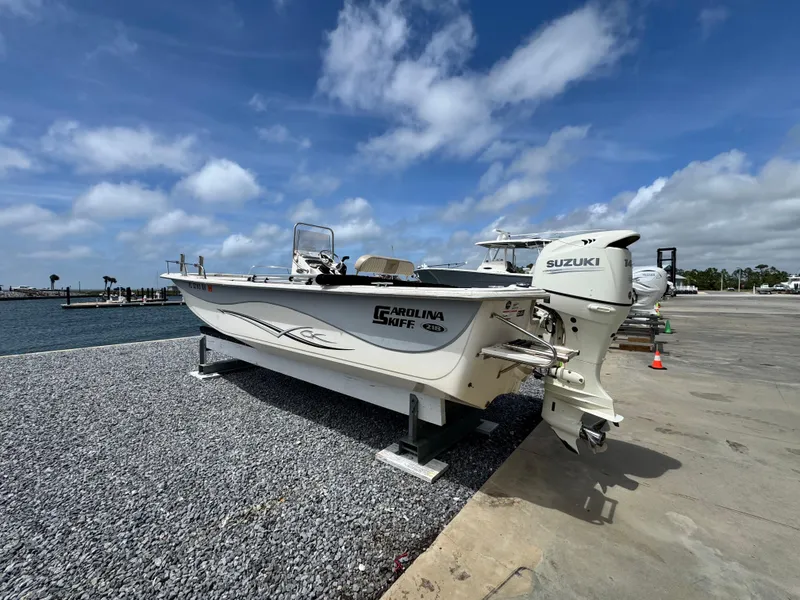 Slide: The Image of 2019 Carolina Skiff 218 DLV boat with Suzuki engine on a sunny day by the water. - 3