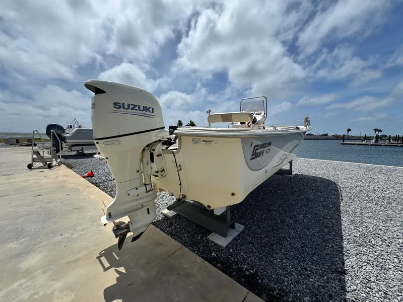 Slide: The Image of 2019 Carolina Skiff 218 DLV boat with Suzuki outboard motor by the water. - 5