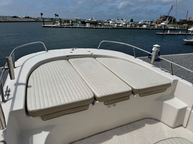 Slide: The Image of 2019 Carolina Skiff 218 DLV boat with cushioned seating, docked at a marina. - 9