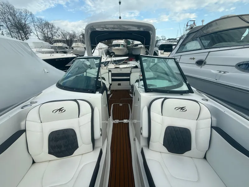 Slide: The Image of 2018 Monterey 298 Super Sport boat with white seating and glass windshields, docked among other boats. - 8