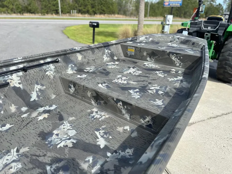 Slide: The Image of 2025 War Eagle 548LDV boat with camouflage interior design, parked near a road. - 3