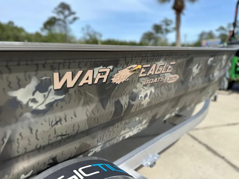 Slide: The Image of 2025 War Eagle 548LDV boat with camouflage design and logo, outdoors on a sunny day. - 6