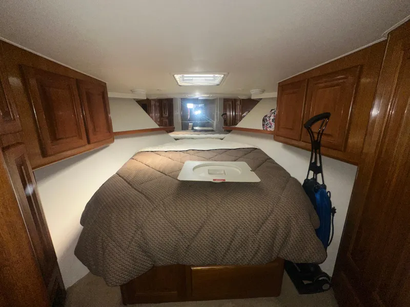 Slide: The Image of Cozy bedroom in 1998 Viking 53 Convertible yacht with wood cabinets and a vacuum cleaner. - 31