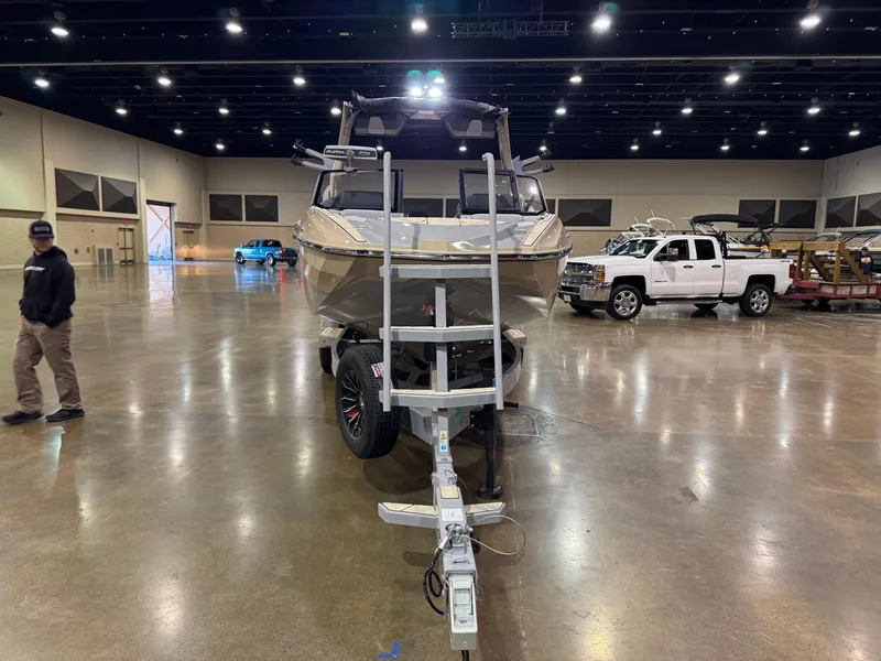 Slide: The Image of 2025 Supra SL boat on trailer in indoor showroom with vehicles in background. - 4