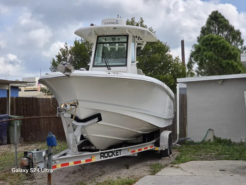 Slide: The Image of 2018 Boston Whaler 250 Outrage boat on trailer, parked outdoors. - 2
