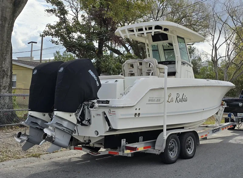 Slide: The Image of 2018 Boston Whaler 250 Outrage boat on trailer with dual engines, parked outdoors. - 4