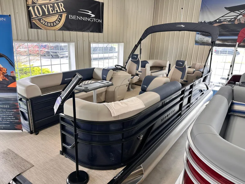 Slide: The Image of 2024 Bennington S Series 22 SSR pontoon boat displayed in showroom with seating and canopy. - 2