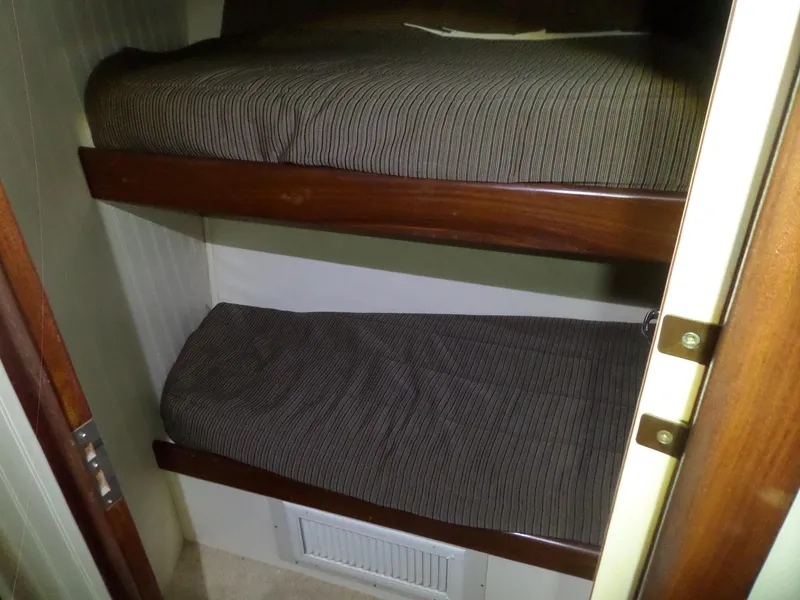 Slide: The Image of Bunk beds in 1988 Hatteras 38 Convertible yacht cabin, featuring wood accents and striped bedding. - 16
