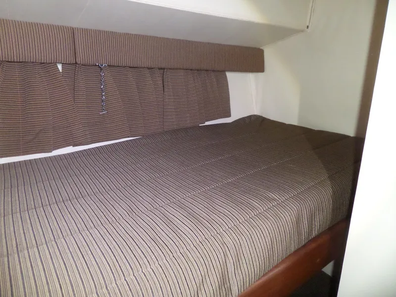 Slide: The Image of 1988 Hatteras 38 Convertible cabin with striped bedding and curtains. - 17