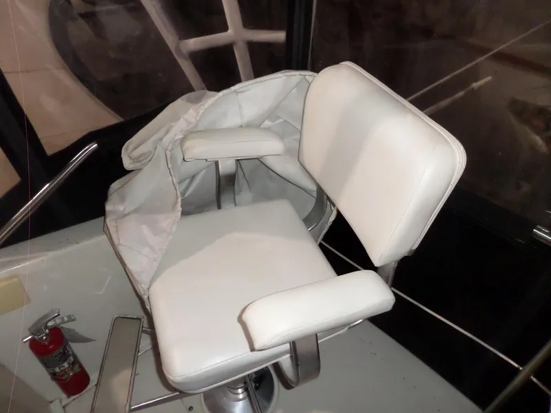 Slide: The Image of Captain's chair on 1988 Hatteras 38 Convertible boat, with white upholstery and armrests. - 47