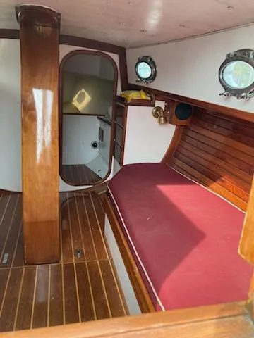 Slide: The Image of Interior of 2000 Hank Hinckley Great Harbor 26 Sloop with wooden finish and red cushioned seating. - 8