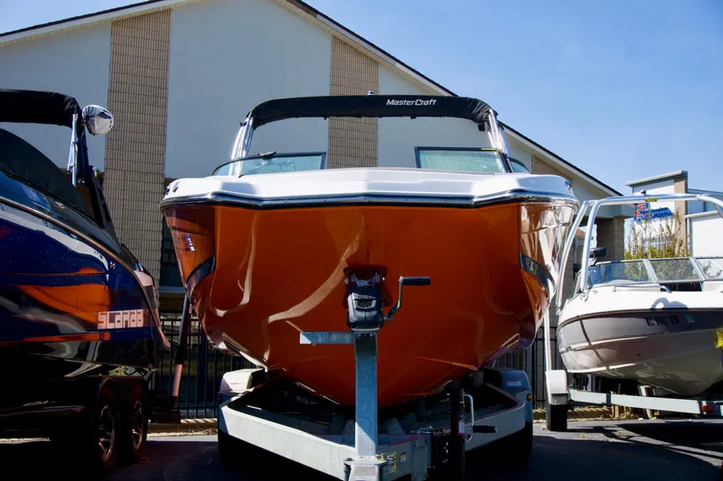Slide: The Image of 2018 MasterCraft NXT22 boat with orange hull on trailer, parked outdoors. - 1