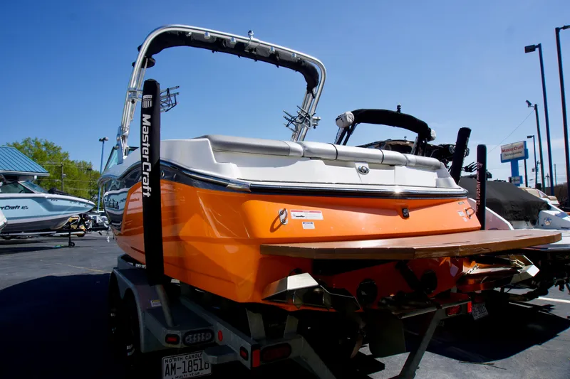 Slide: The Image of 2018 MasterCraft NXT22 boat with orange hull, parked on a trailer in a sunny outdoor setting. - 3