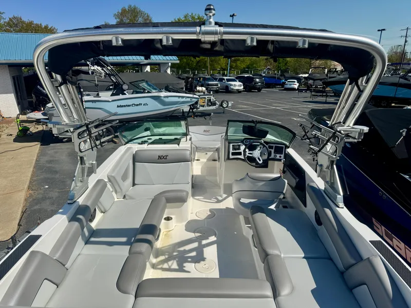 Slide: The Image of 2018 MasterCraft NXT22 boat interior with seating and steering wheel, parked outdoors. - 9