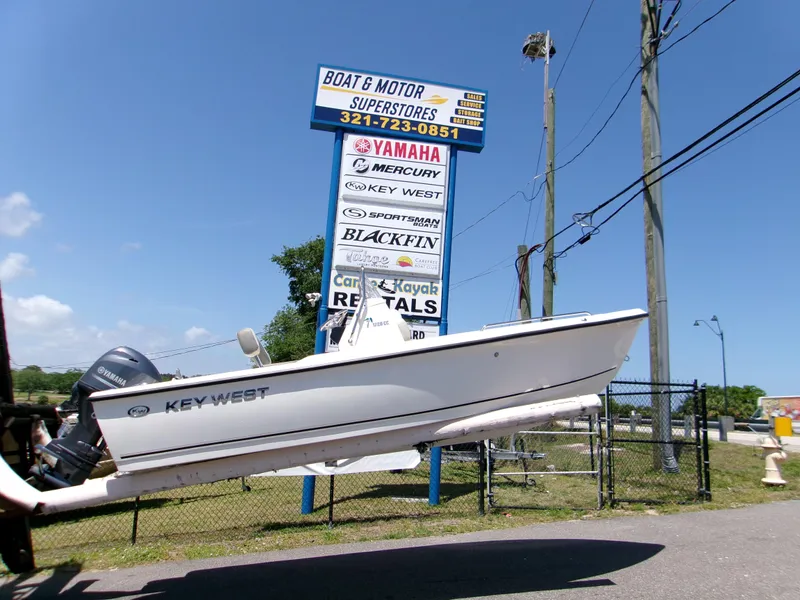 The Image of Key West 1720 boat near dealership sign, showcasing various marine brands. - 1