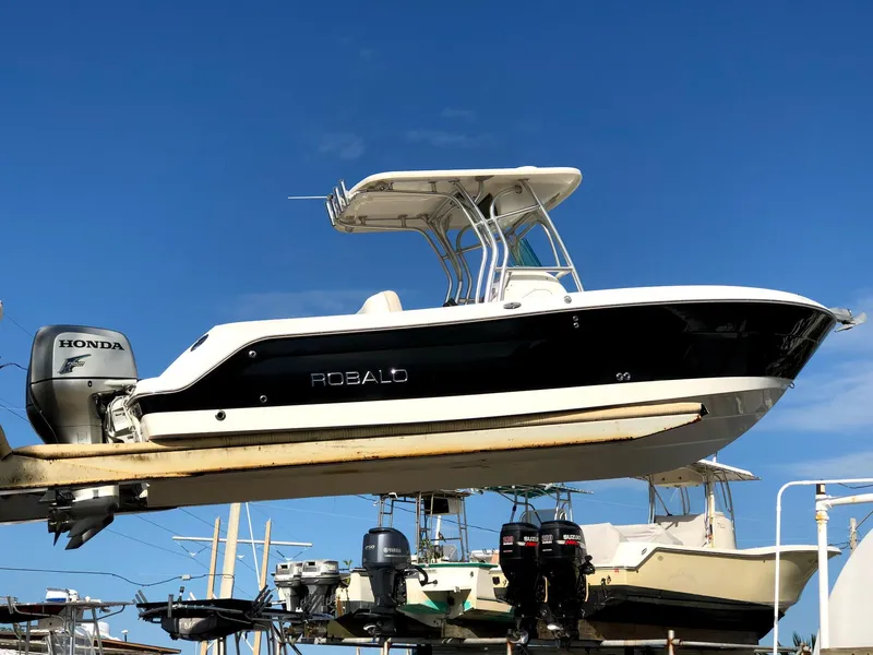 Slide: The Image of 2007 Robalo R240 Center Console boat with Honda outboard motor, displayed on a lift. - 2