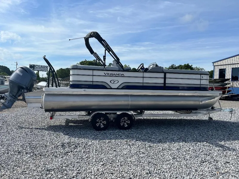 Slide: The Image of 2025 Veranda VS22RC pontoon boat on trailer, parked on gravel lot under clear sky. - 0