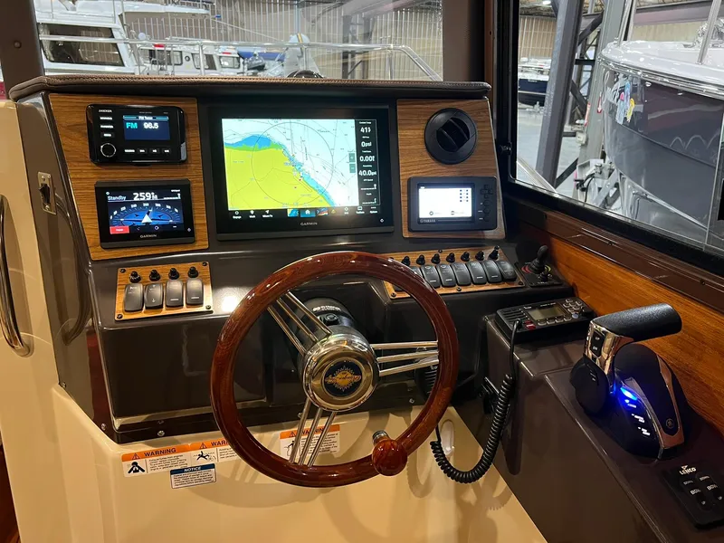 Slide: The Image of 2023 Ranger Tugs R-25 helm with navigation screens and wooden steering wheel. - 12