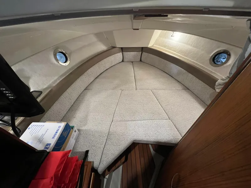 Slide: The Image of 2023 Ranger Tugs R-25 cabin interior with cozy seating and porthole windows. - 13