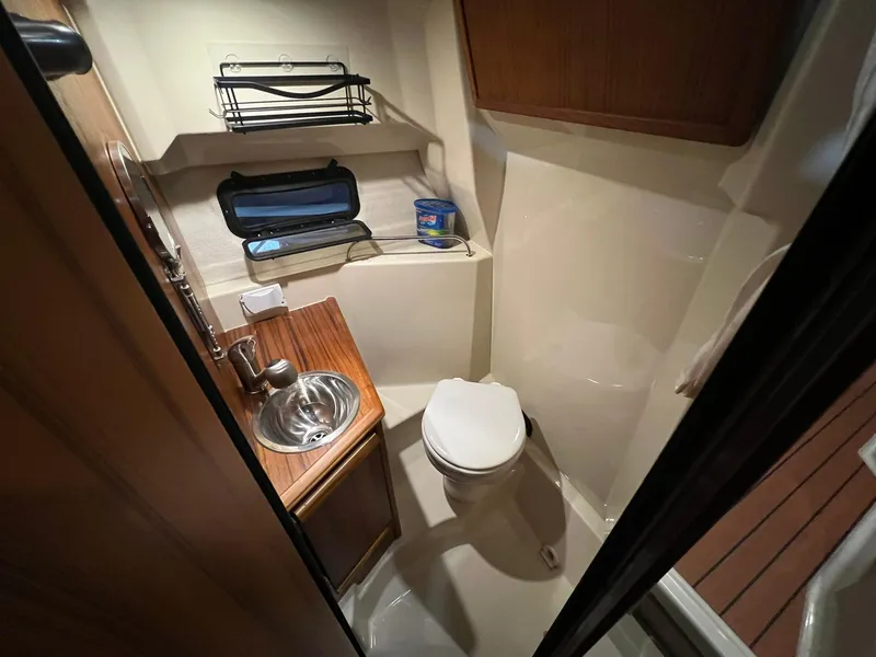 Slide: The Image of 2023 Ranger Tugs R-25 boat bathroom with sink, toilet, and storage shelves. - 14