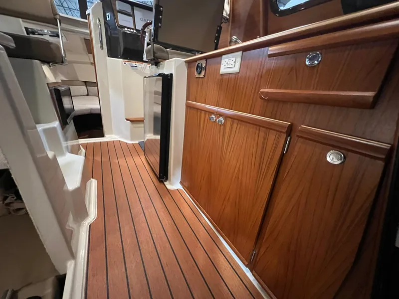 Slide: The Image of 2023 Ranger Tugs R-25 interior with wood cabinetry and flooring, showcasing modern design. - 17
