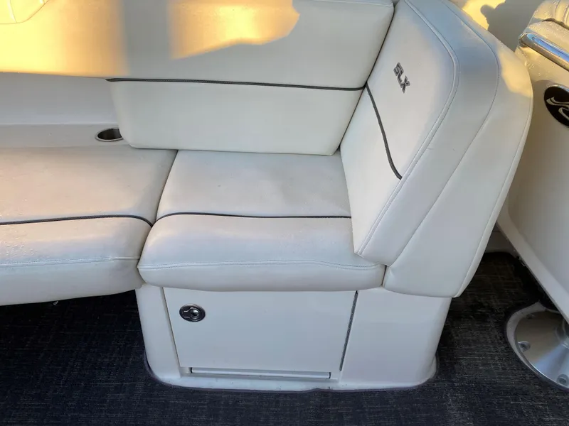 Slide: The Image of 2006 Sea Ray 270 SLX boat interior seating with white upholstery and storage compartment. - 6