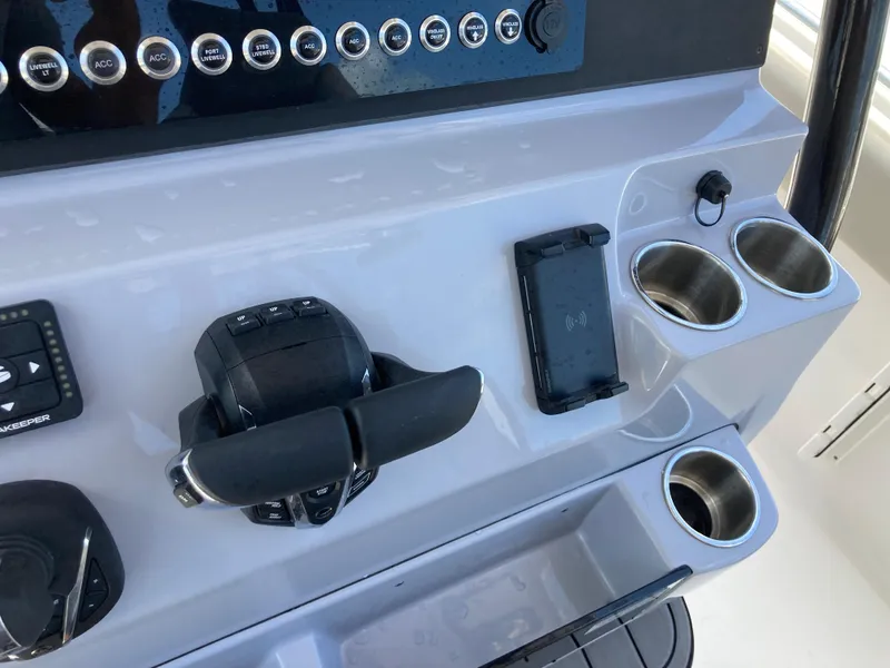Slide: The Image of Control panel of 2025 Key West 291FS boat with throttle, cup holders, and smartphone holder. - 12