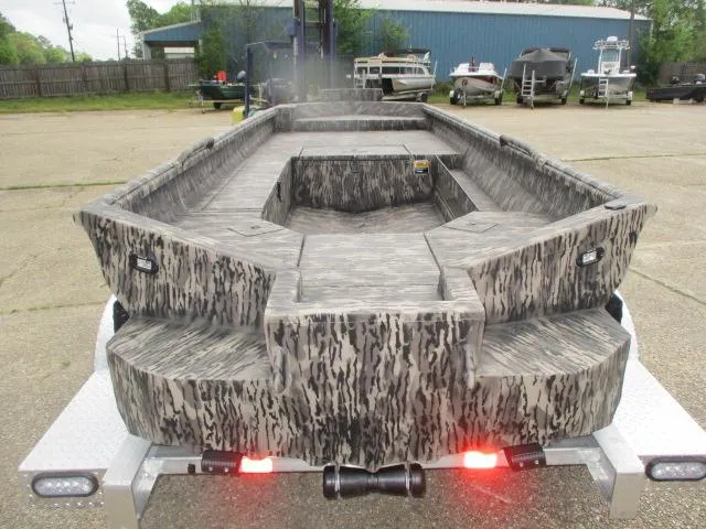 Slide: The Image of 2025 Reaper Boats 756-1381 model, camo design, parked on trailer in industrial area. - 3