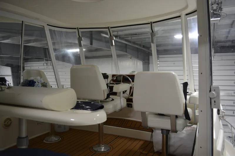 Slide: The Image of Interior view of 2001 Silverton 453 Motor Yacht helm with white seating and wooden flooring. - 23