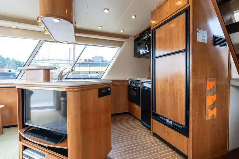 Slide: The Image of 2003 Meridian 490 Pilothouse interior with wood cabinetry, kitchen appliances, and large windows. - 6