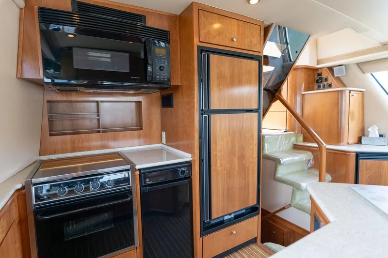 Slide: The Image of 2003 Meridian 490 Pilothouse kitchen with wood cabinetry, stove, microwave, and stairs. - 7