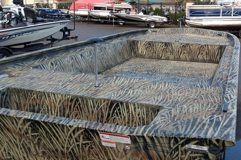 Slide: The Image of 2025 Tracker GRIZZLY 1860 Utility boat with camouflage design, parked outdoors. - 3