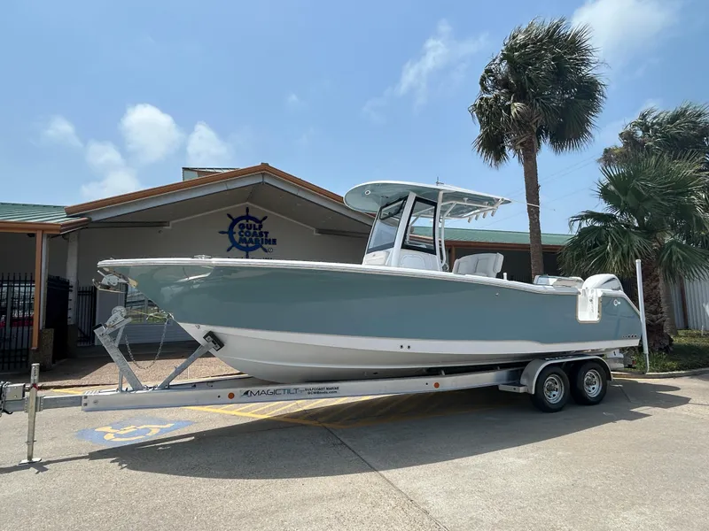 Slide: The Image of 2025 Sea Hunt Gamefish 27 boat on trailer, parked outdoors near palm trees. - 1