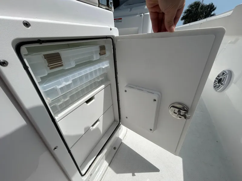 Slide: The Image of 2025 Sea Hunt Gamefish 27 storage compartment with open door, showcasing organized interior. - 12