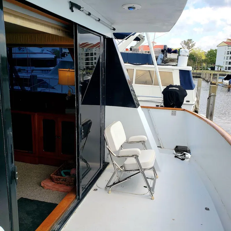 Slide: The Image of 1988 Viking 55 Motoryacht Walkaround with open deck, folding chair, and marina view. - 11