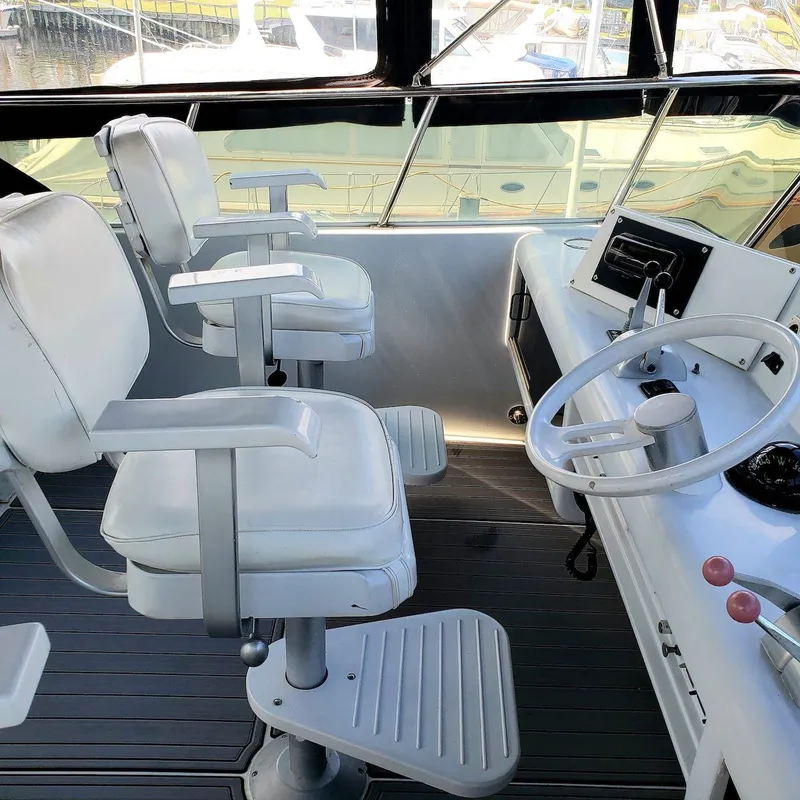 Slide: The Image of 1988 Viking 55 Motoryacht Walkaround helm with white captain chairs and steering wheel. - 15